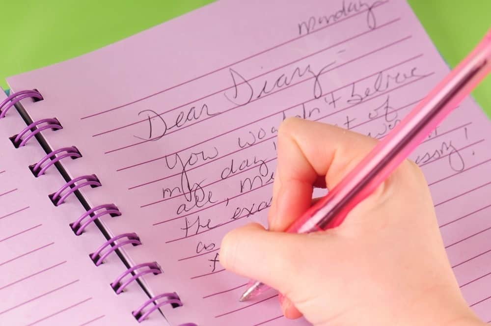 girl writing in pink diary